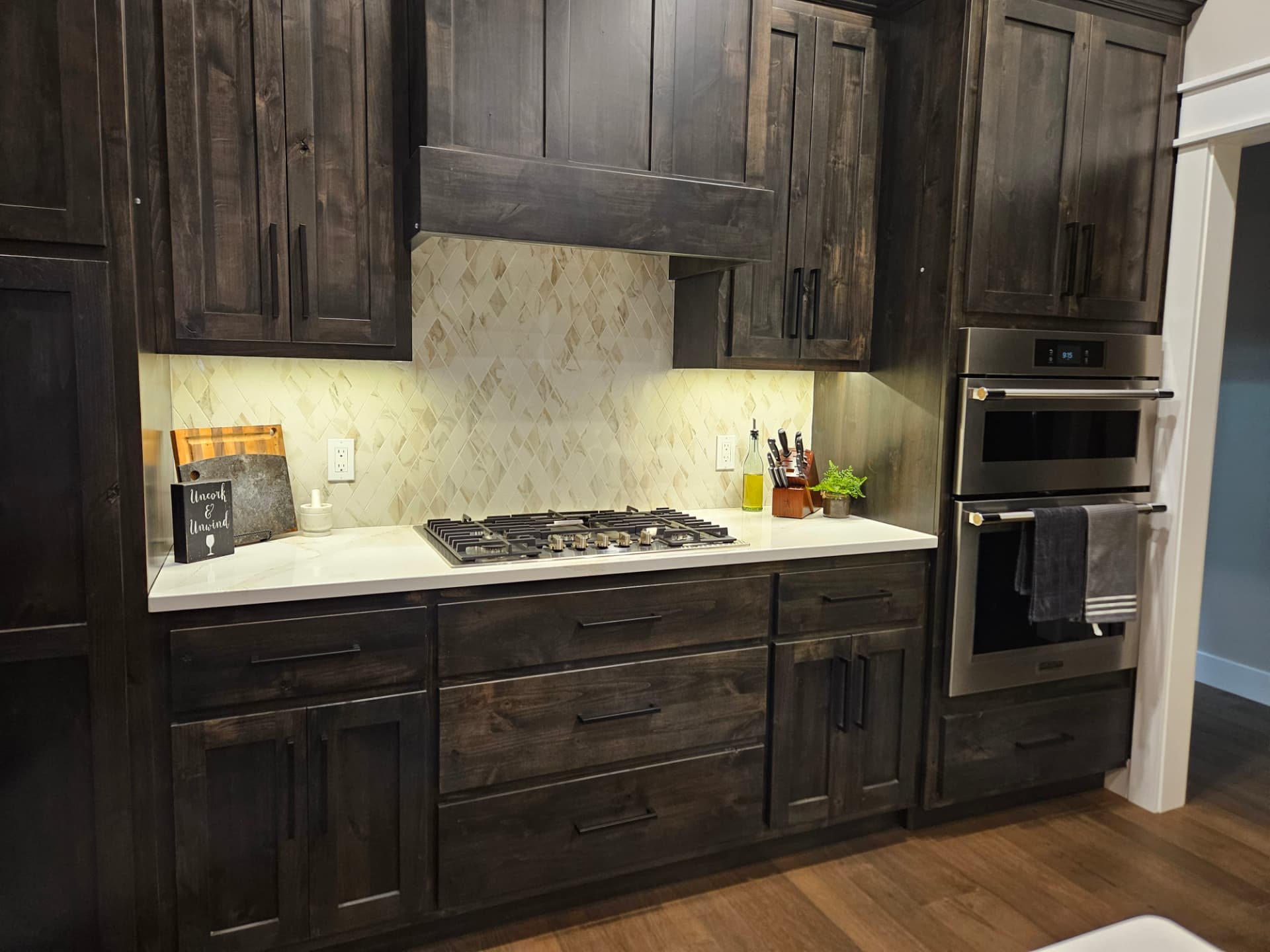Custom dark wood kitchen cabinetry with built-in appliances and cooktop in a Midwest Custom Homes home.